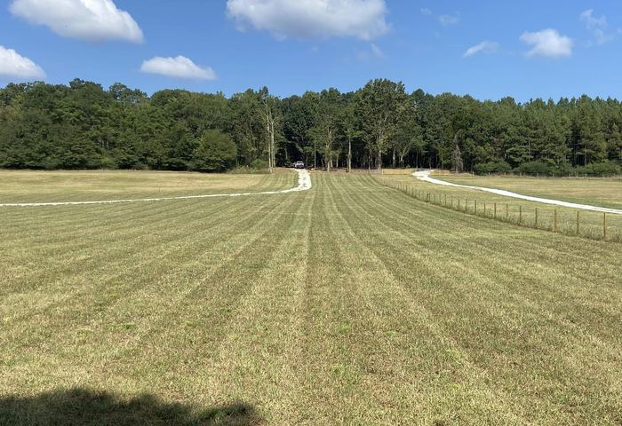 Mowed open land with gravel driveway and fence posts on a prepared Millwood lot in North Georgia